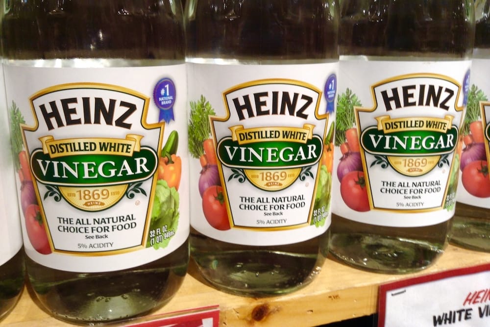 Image of three bottles of distilled white vinegar sitting on a shelf